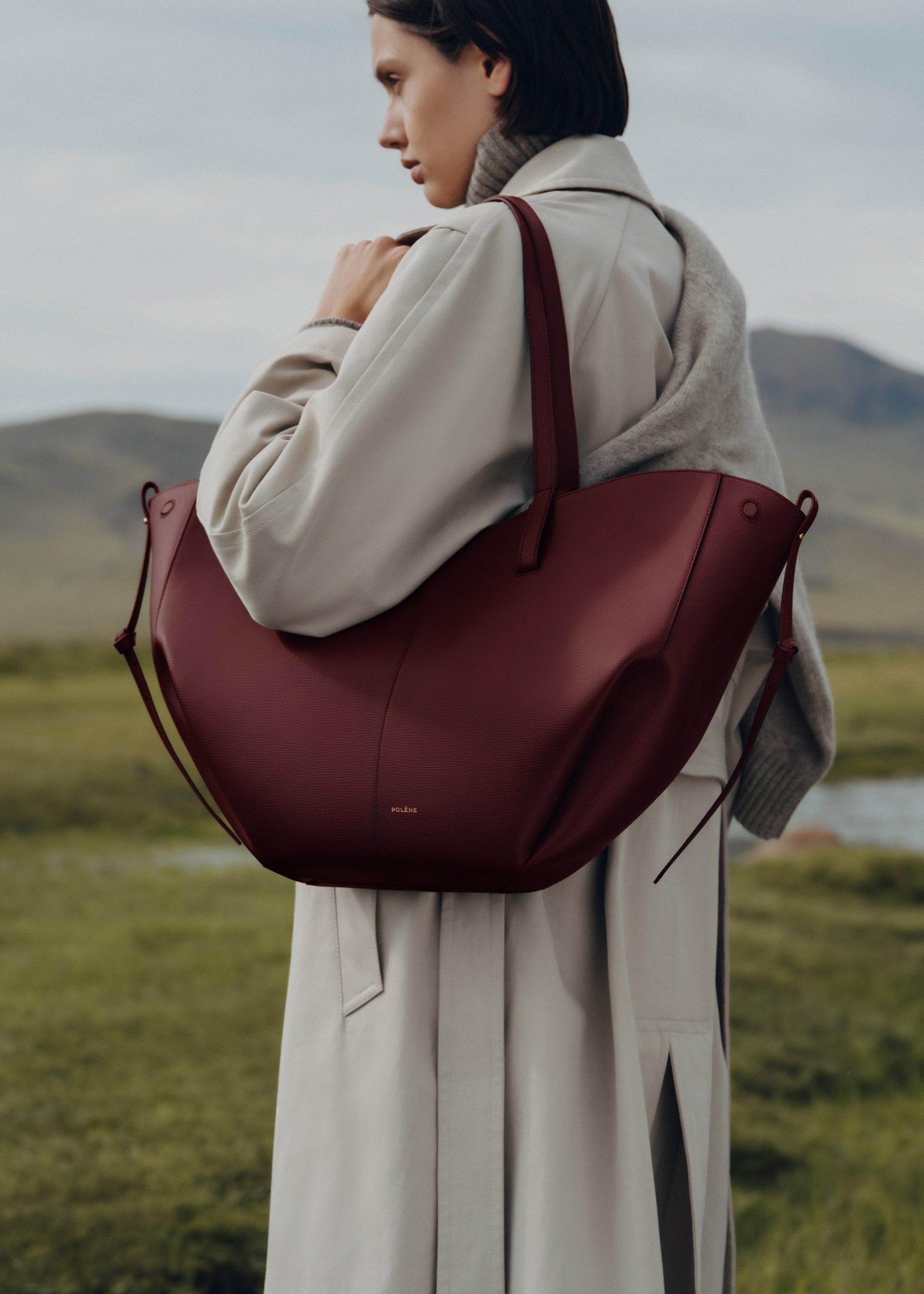 Bolso de mano Polène Cyme en piel granulada de color cereza negra, con detalles elegantes y acabado de alta calidad.