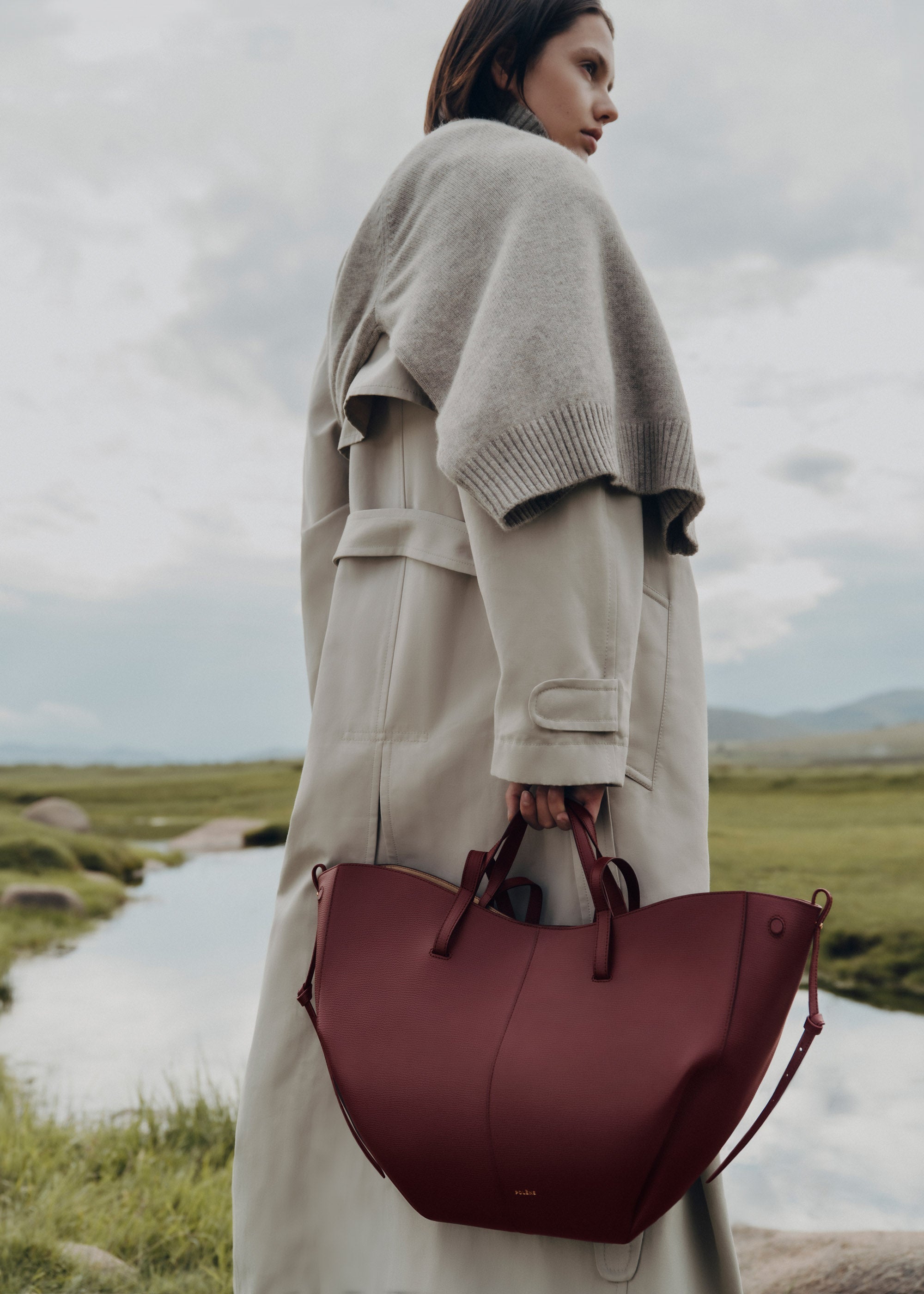 Bolso de mano Polène Cyme en piel granulada de cereza negra, diseño elegante y moderno, con detalles en la superficie.