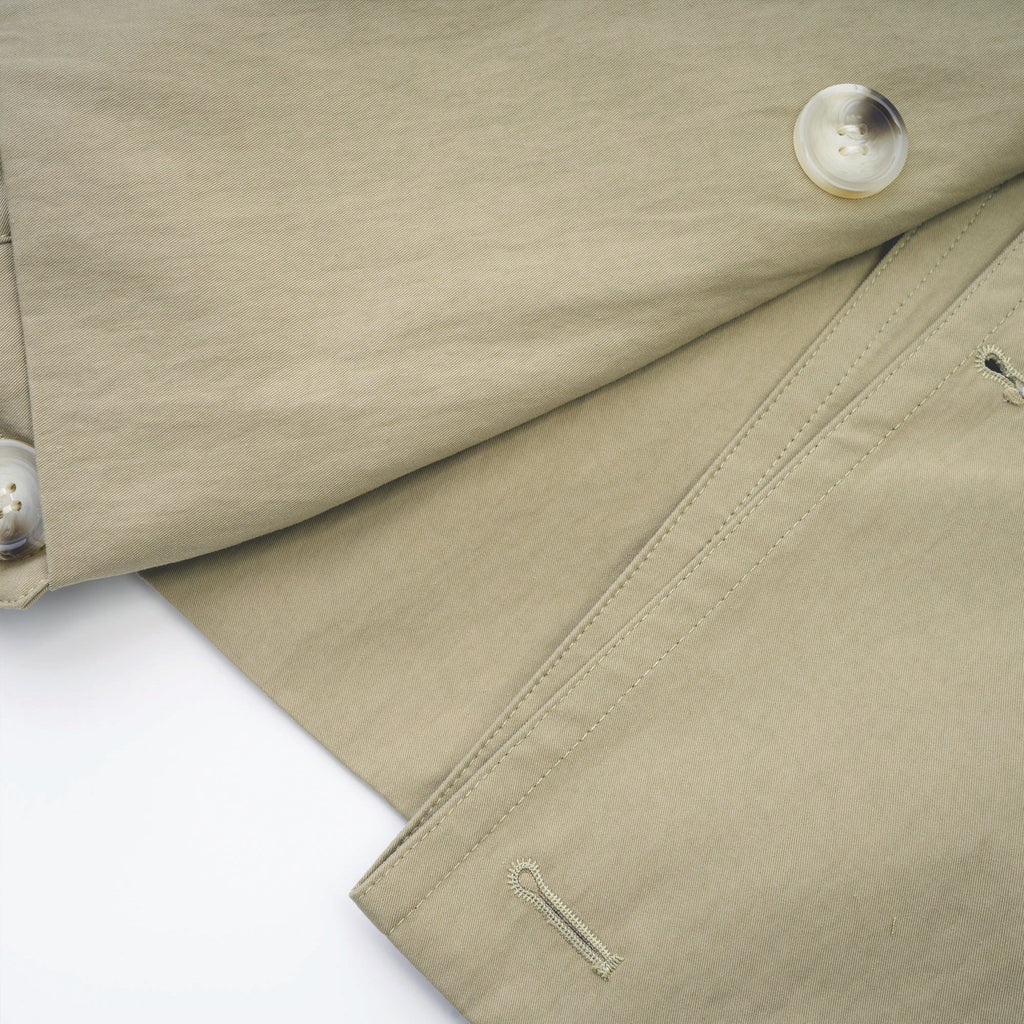 Abrigo trench con cinturón de la marca MRNewyork, color beige, diseño clásico con mangas largas y cuello.
