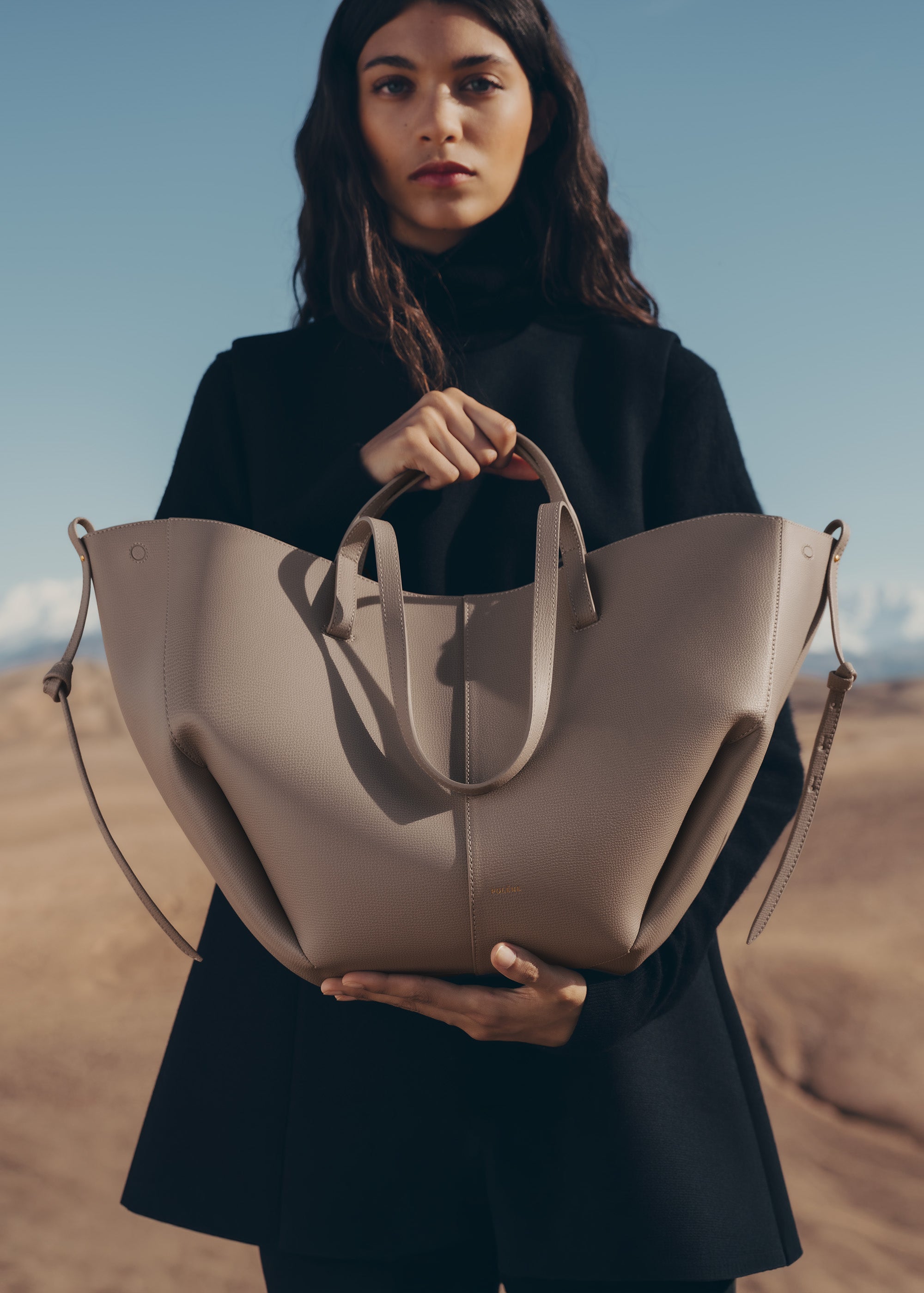 Bolso de mano Polène Cyme en piel granulada gris topo, con diseño elegante y detalles en acabado de alta calidad.