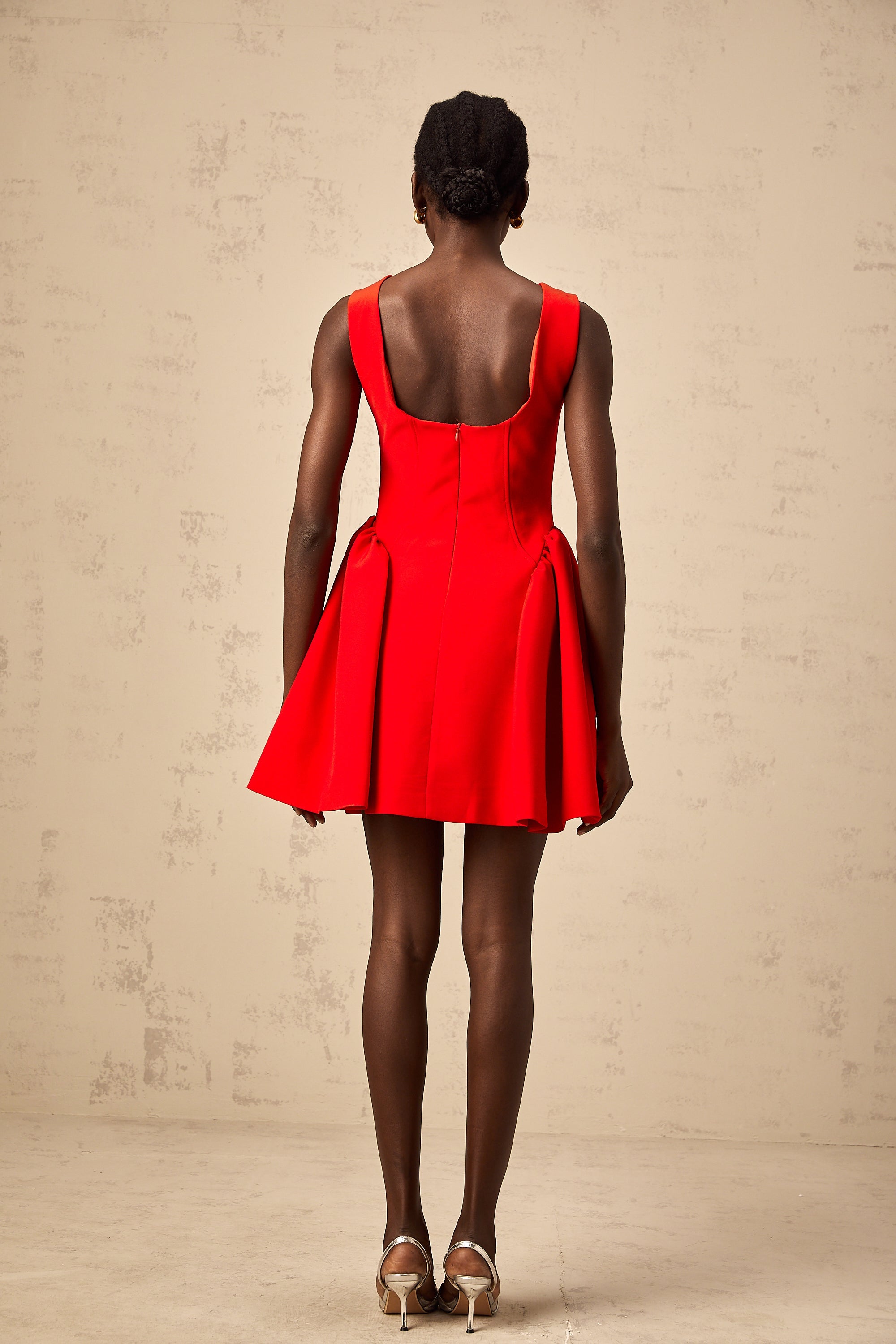 Vestido mini sin mangas rojo Yulia de corte acampanado, estilo ajustado y moderno, en una modelo luciendo el diseño.