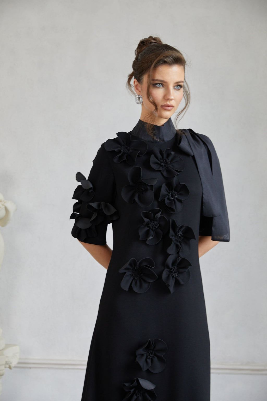 Vestido maxi negro Bridal Isidora con lazo y aplicación floral, mostrando su diseño elegante y detalles en la tela.