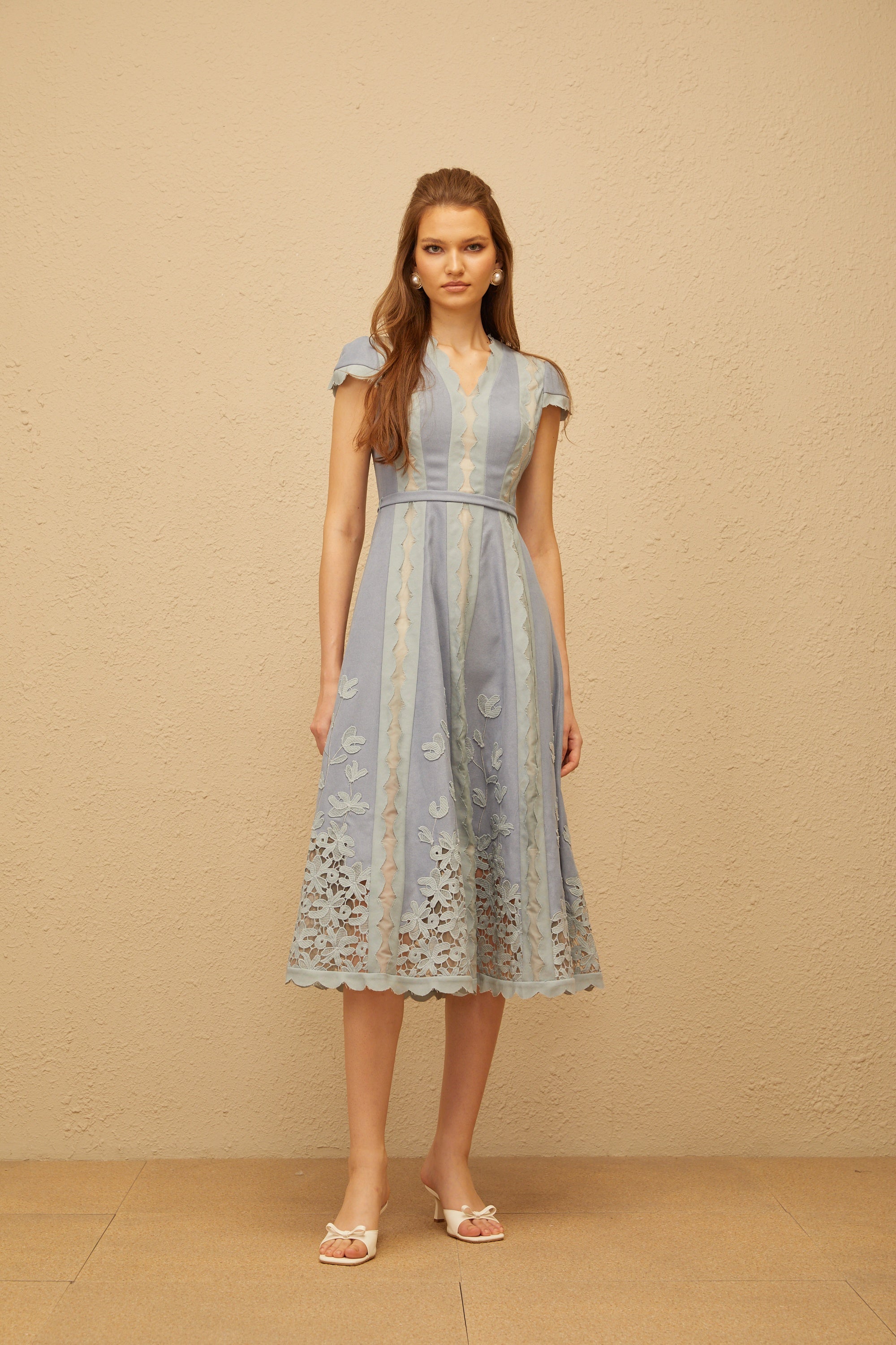 Vestido midi azul Amália con bordado floral y ribetes en ondas, de MRNewyork, mostrando su diseño elegante y detalles decorativos.