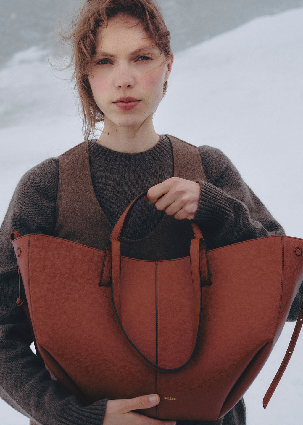 Bolso de mano Polène Cyme en arcilla roja con textura granulada, diseño elegante y material de alta calidad.