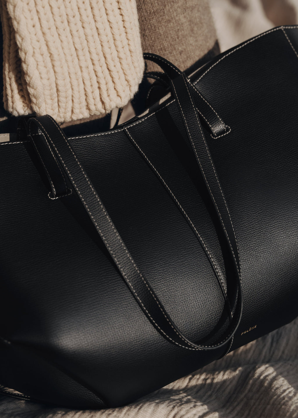 Bolso de mano Polène Cyme en piel negra granulado con costuras contrastadas, diseño elegante y detalles en la superficie.
