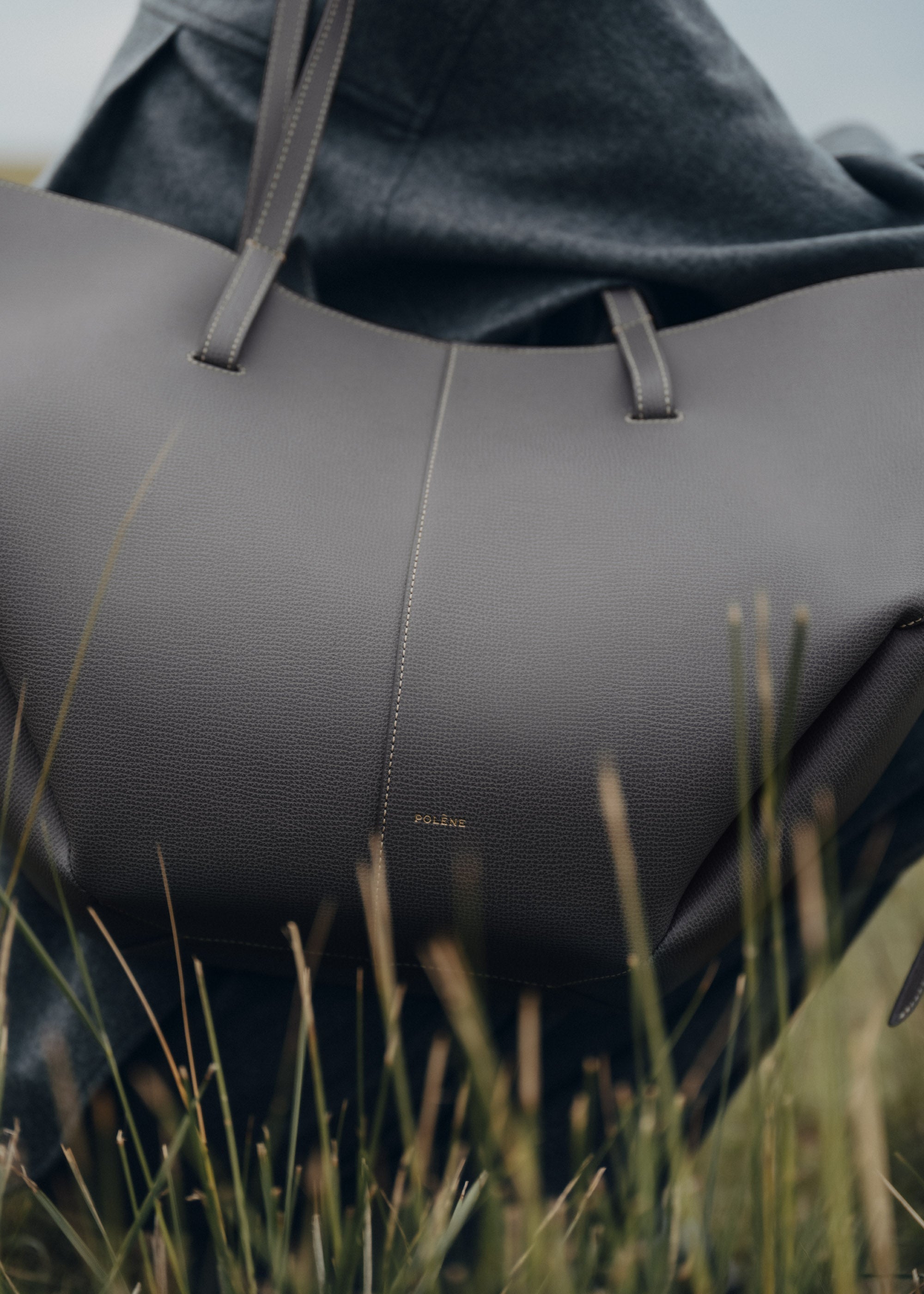Bolso de mano Polène Cyme con piedra piel granulada en color neutro, detalles de textura y diseño elegante.