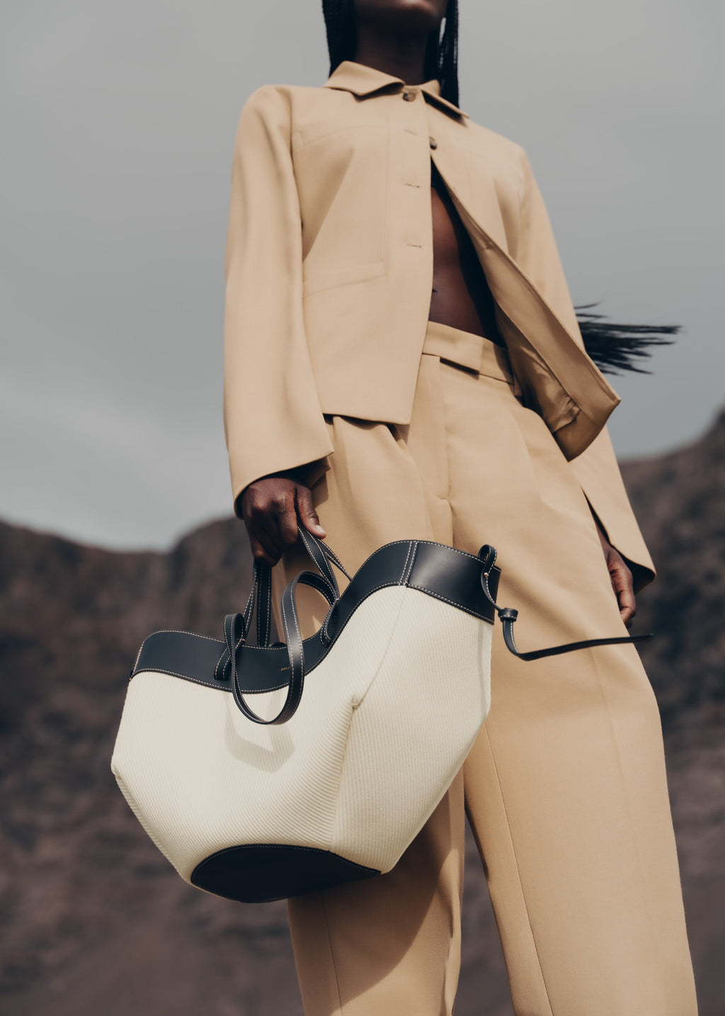 Bolso de mano negro trenzado Cyme de la marca Polène, con diseño elegante y detalles en cuero.