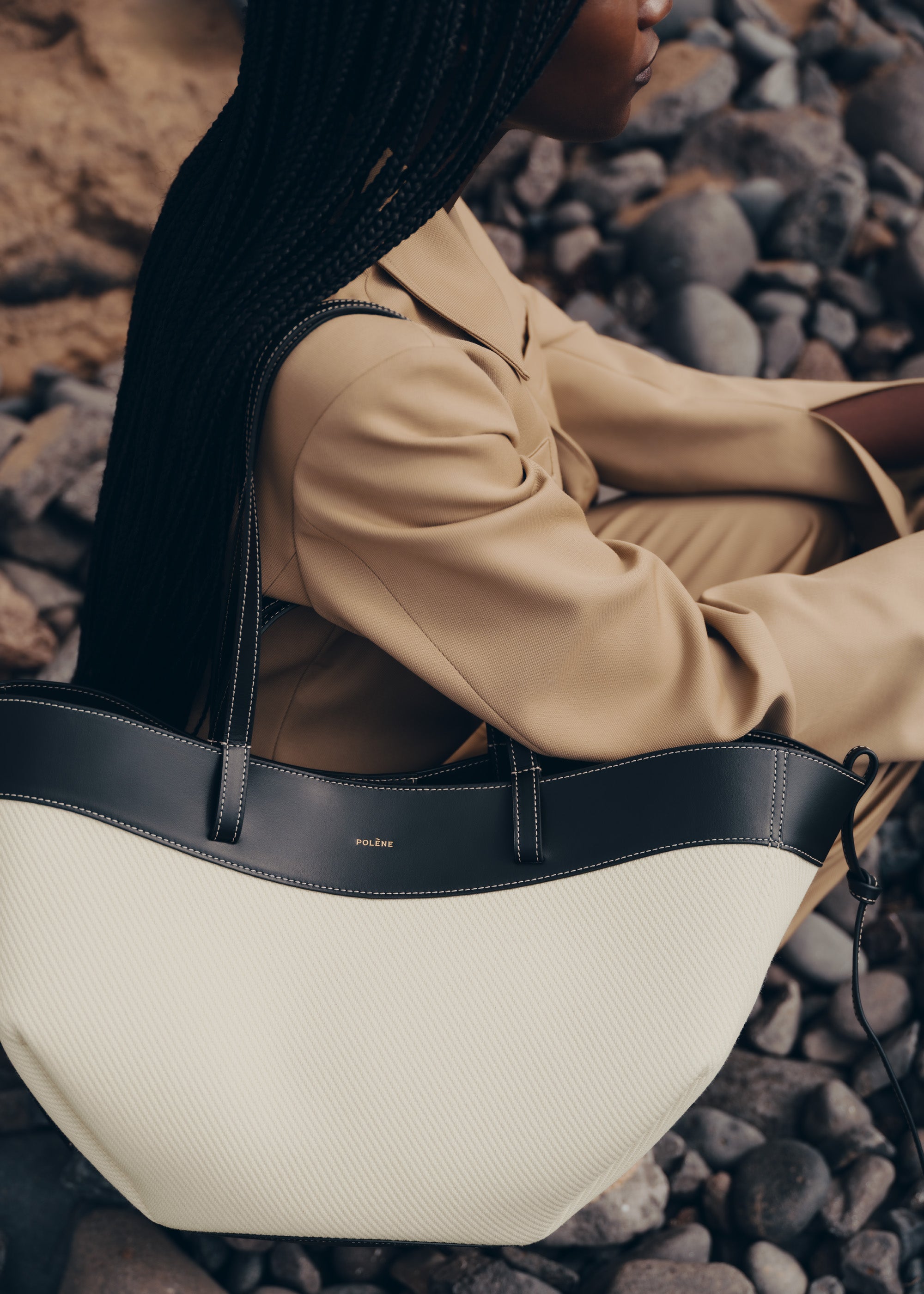 Bolso de mano negro trenzado Cyme de la marca Polène, con detalles de textura y diseño elegante.