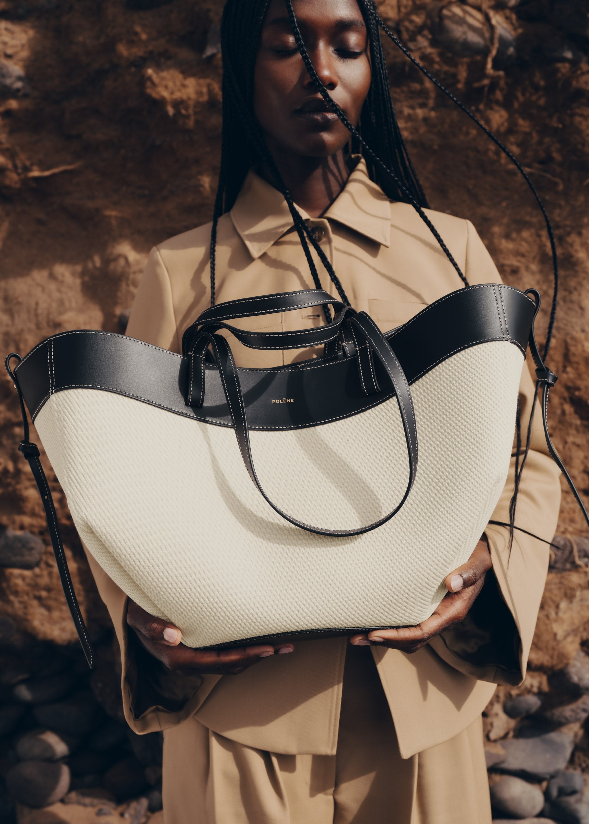 Bolso de mano negro trenzado Polène Cyme, estilo elegante y moderno con detalles de trenza en la parte superior.