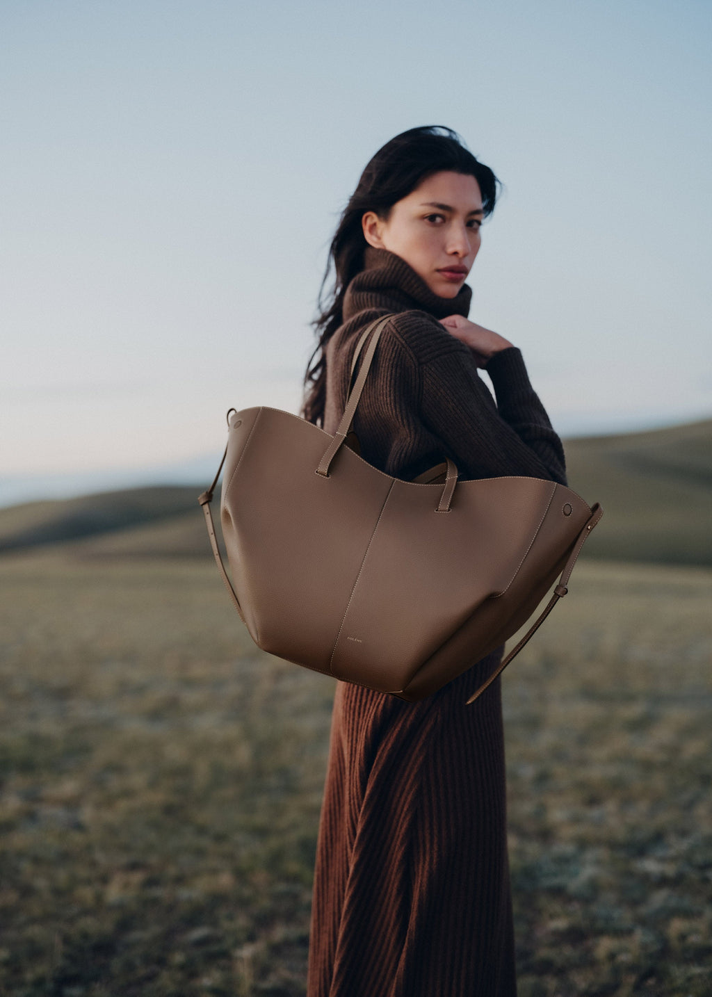 Bolso de mano Polène Cyme con raíz de piel granulada en tono alezán, detalles elegantes y acabado texturizado en la superficie.