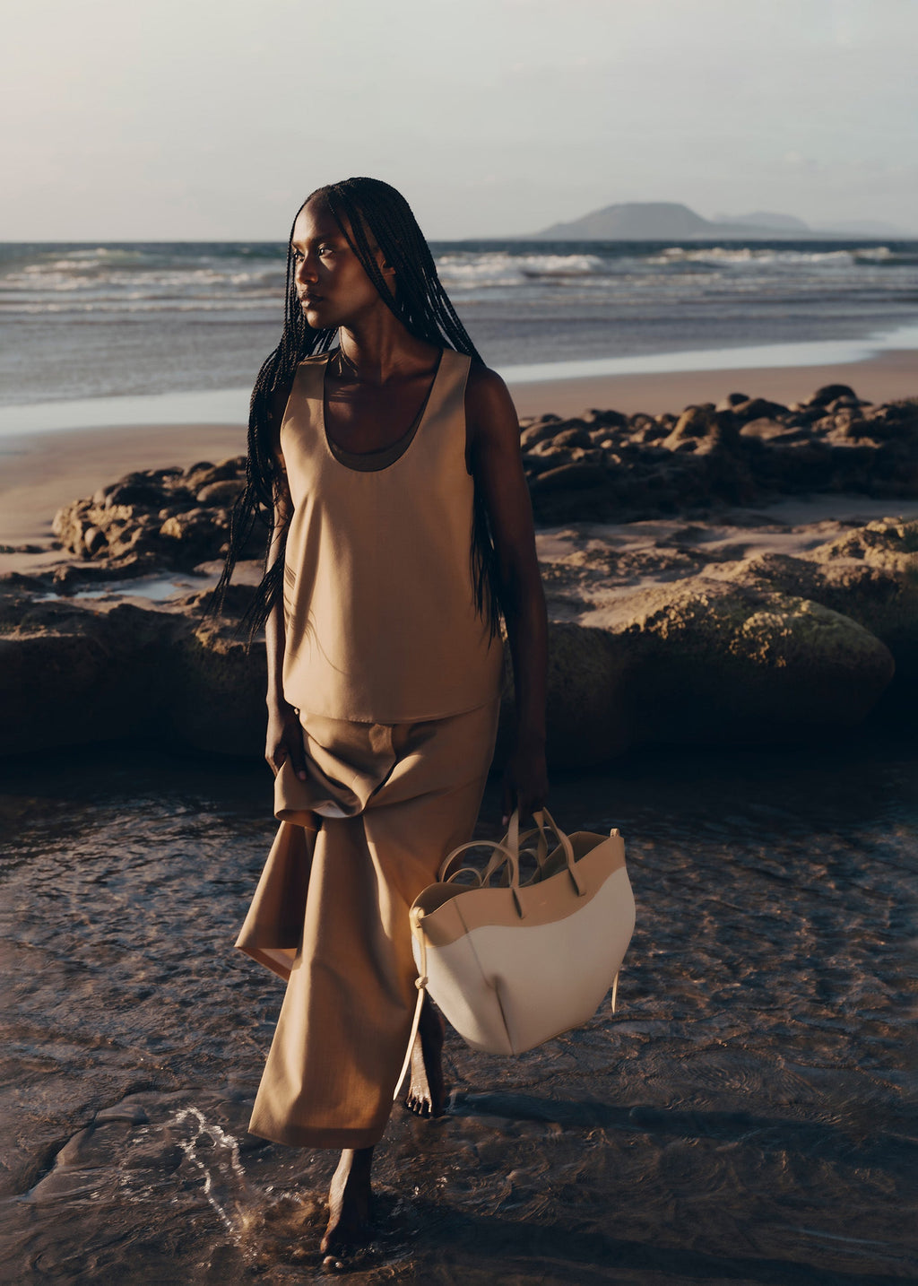 Bolso de mano trenzado en beis de la marca Polène, estilo elegante y sofisticado, con detalles de tejido en el diseño.