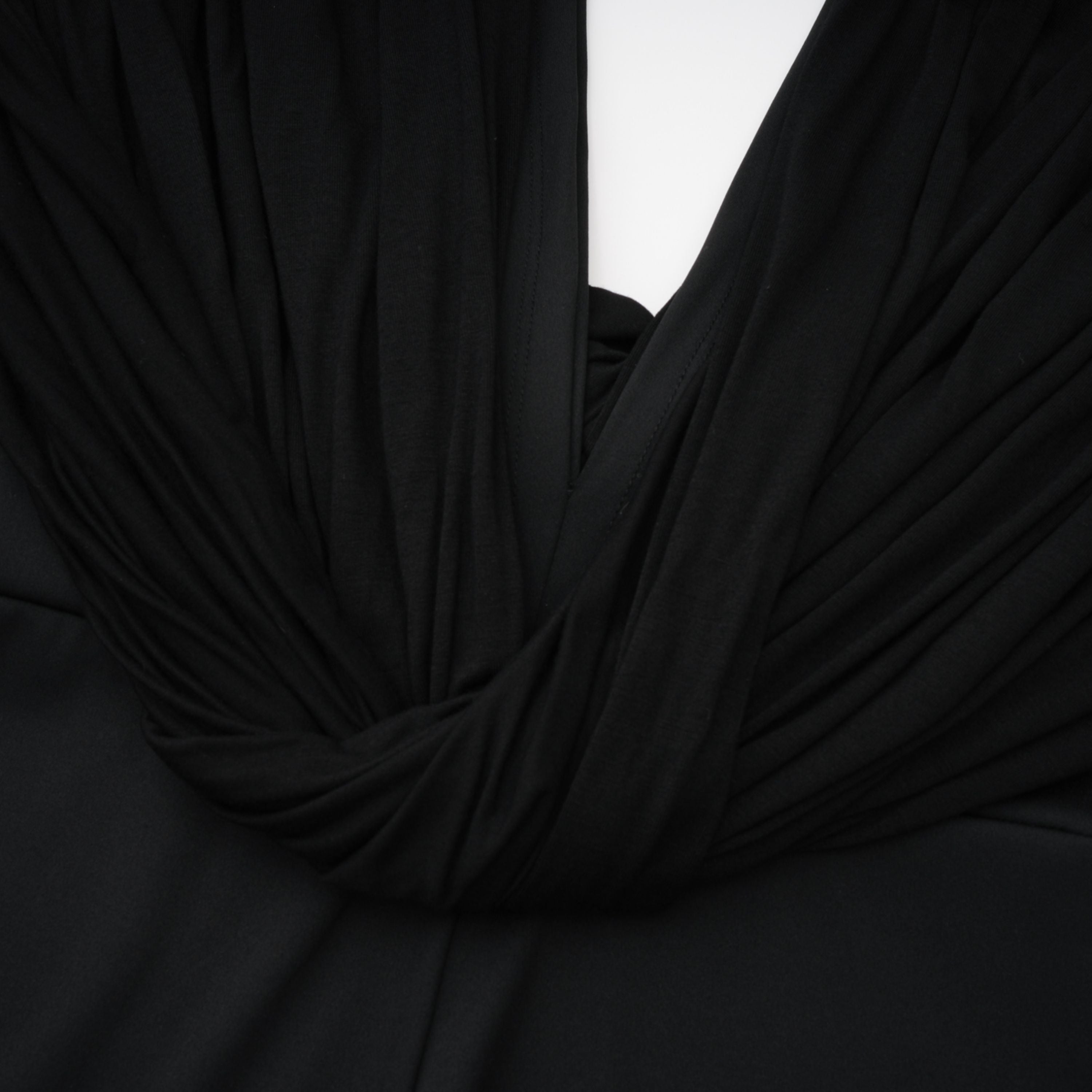 Mono negro Gianina de Bridal con escote en V profundo y drapeado, mostrando su diseño elegante y ajustado en la imagen.