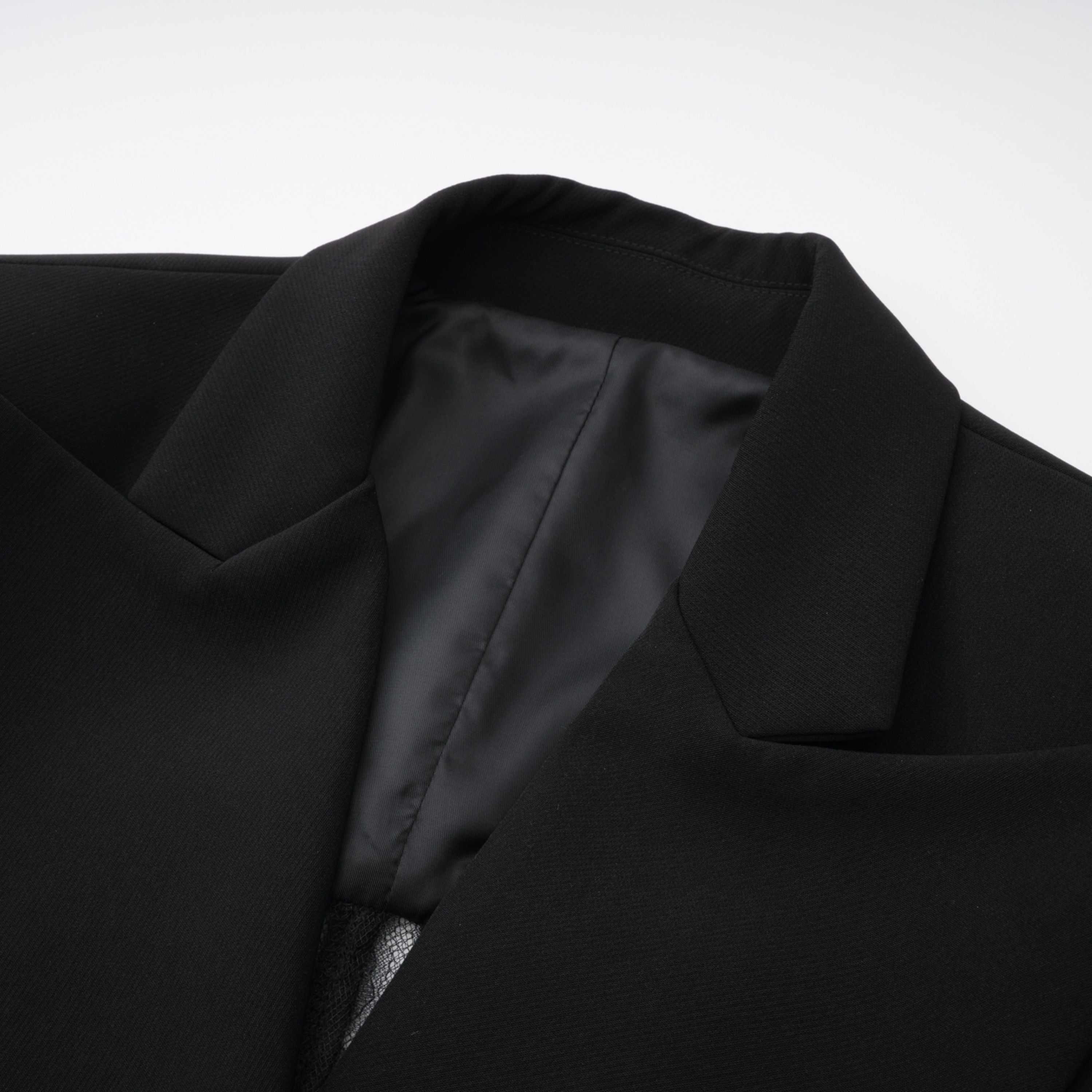 Blazer negro con panel de encaje floral de la marca Bridal, con diseño elegante y detalles delicados en la imagen.