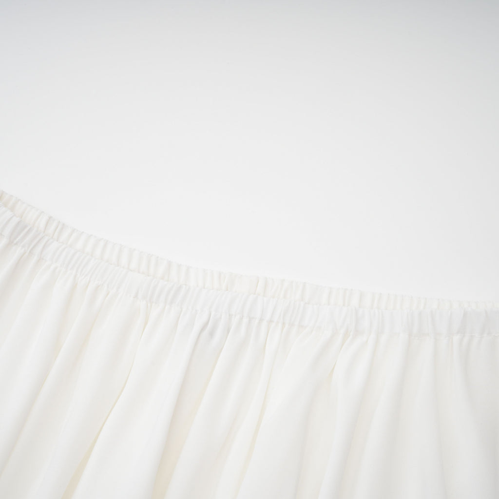 Conjunto de vestido y falda blancos con adornos de la marca Bridal, mostrando detalles elegantes y tela delicada.