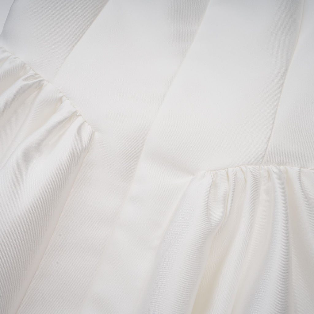 Vestido midi blanco Amandine con espalda abierta y mangas cap en la imagen. Diseño elegante y moderno para ocasiones especiales.