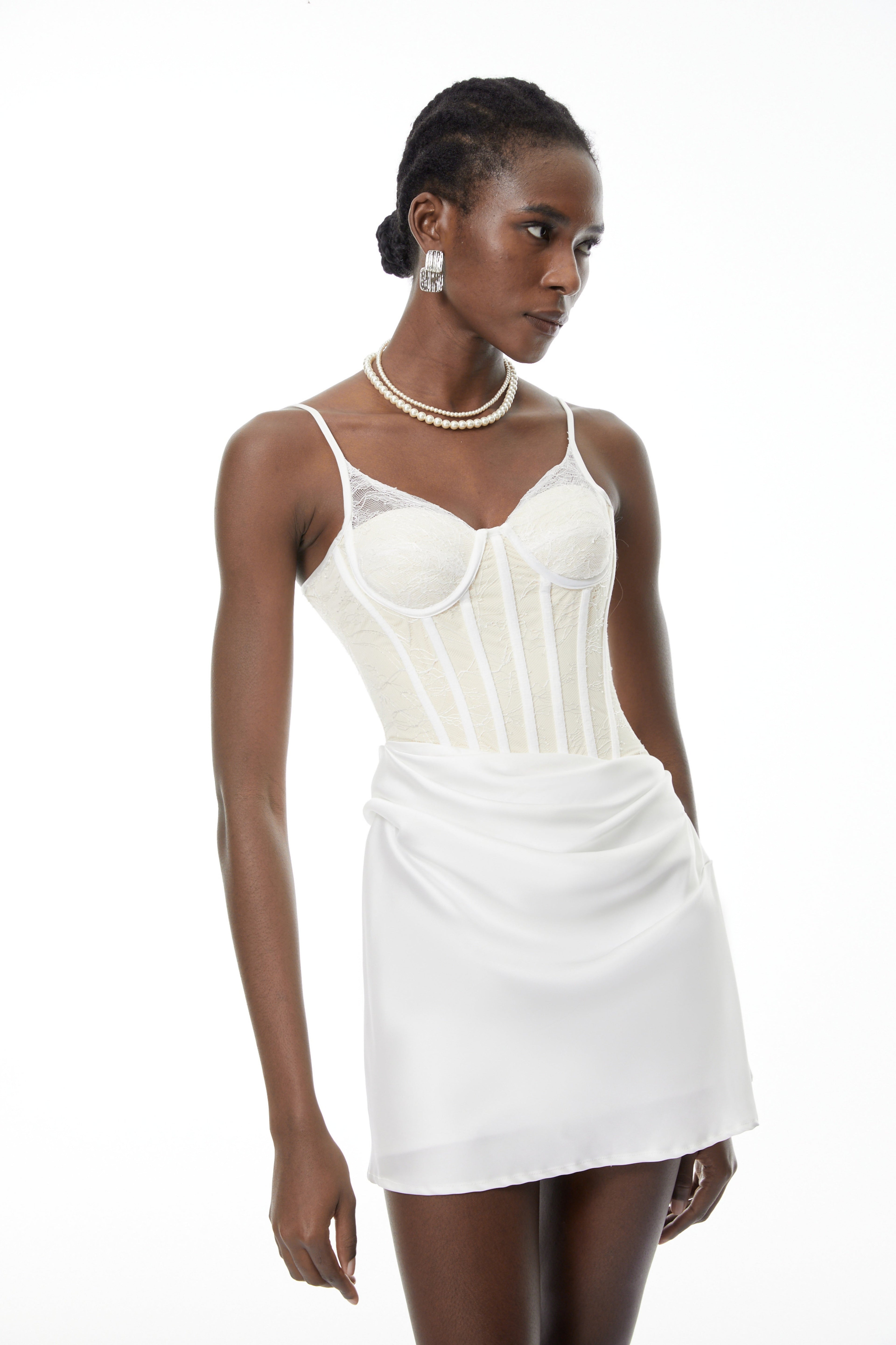 Vestido mini blanco ajustado Eufrosina de MRTokyo con paneles de encaje y escote en V, sobre un fondo neutro.