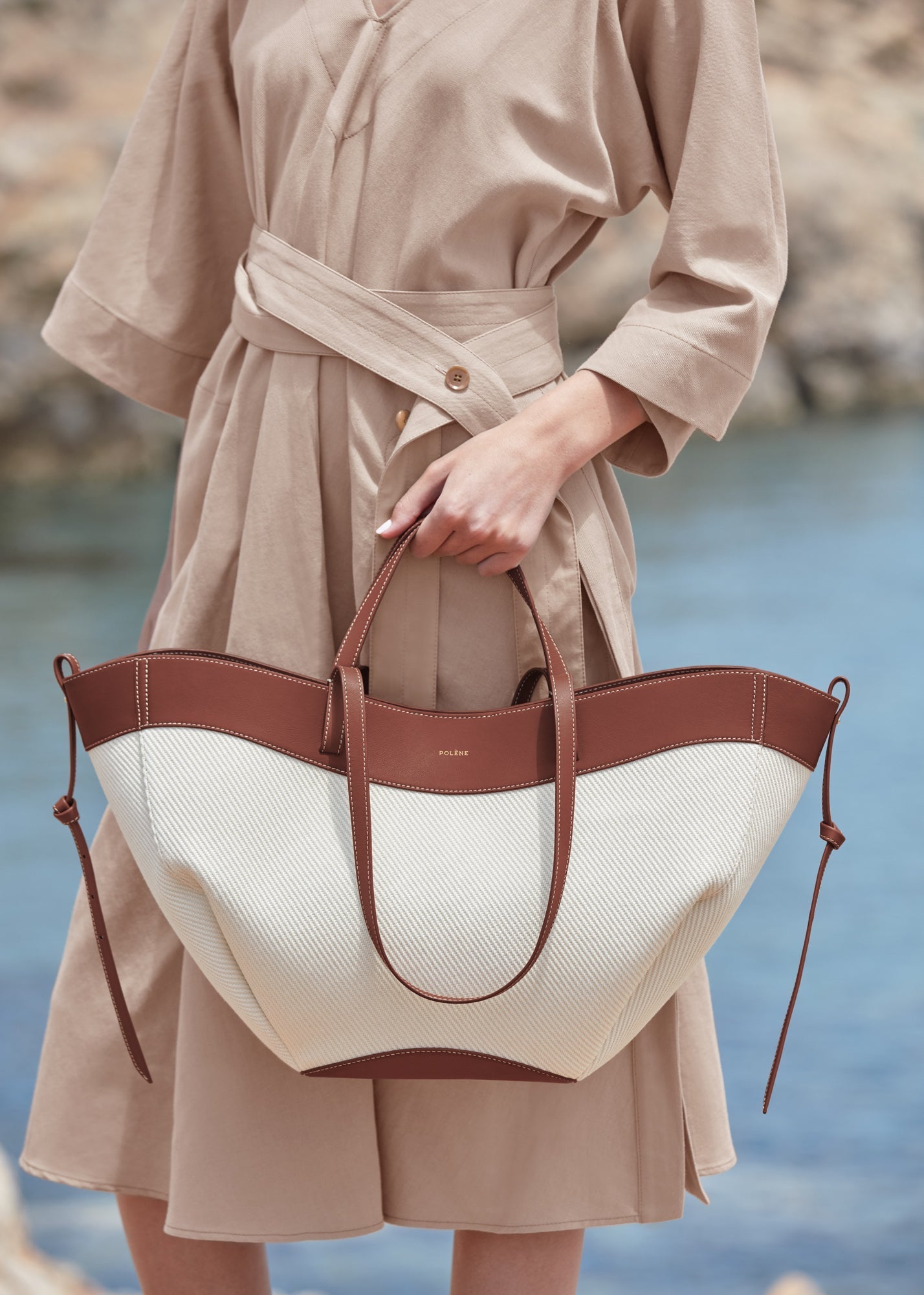 Bolso de mano trenzado en color coñac de la marca Polène, con detalles elegantes y acabado de alta calidad.
