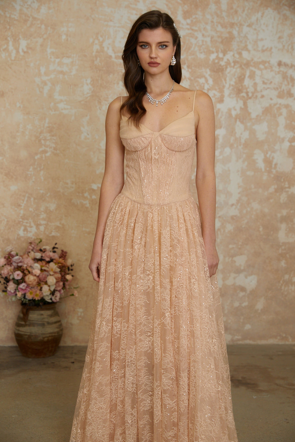 Vestido largo de encaje plisado en tono neutro de la marca MRNewyork, con corsé brillante y diseño elegante.